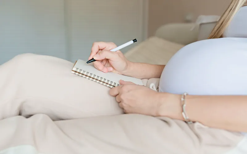 Nahaufnahme: Schwangere Frau schreibt Checkliste für die Geburt.